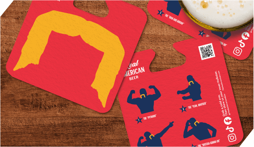 A set of bright red coasters with a yellow silhouette of a mustache and blue wrestler poses, placed on a wooden table with a glass of beer partially visible.