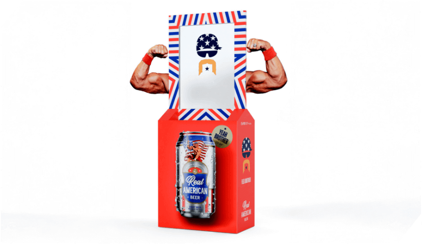 A retail display for Real American Beer featuring a patriotic design, a beer can, and muscular cutout arms flexing on either side.