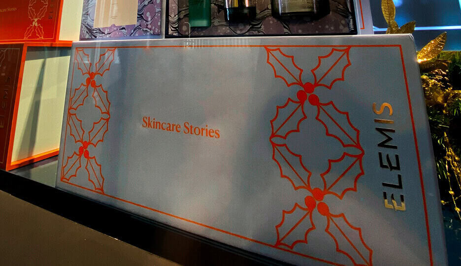 Close-up of an Elemis “Skincare Stories” gift box decorated with red holly motifs and branding.